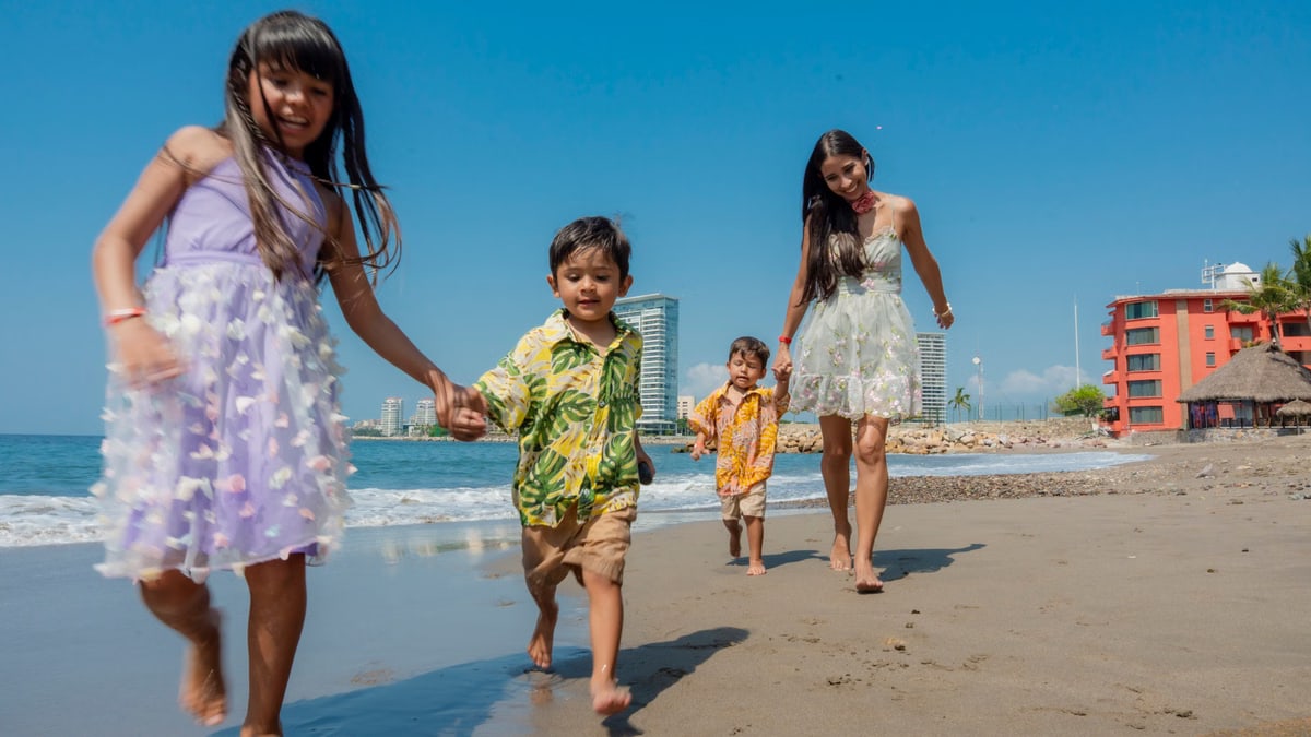 Cheerful family playing and running on a sunny beach, enjoying a vacation day together.